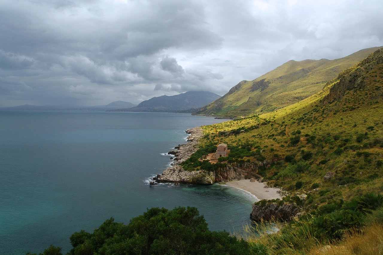 Panorama del paese sardo con case colorate e mare cristallino, simile a un set cinematografico.