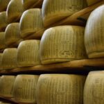 Visita guidata in un caseificio del borgo del parmigiano, con formaggi in esposizione e turisti curiosi.
