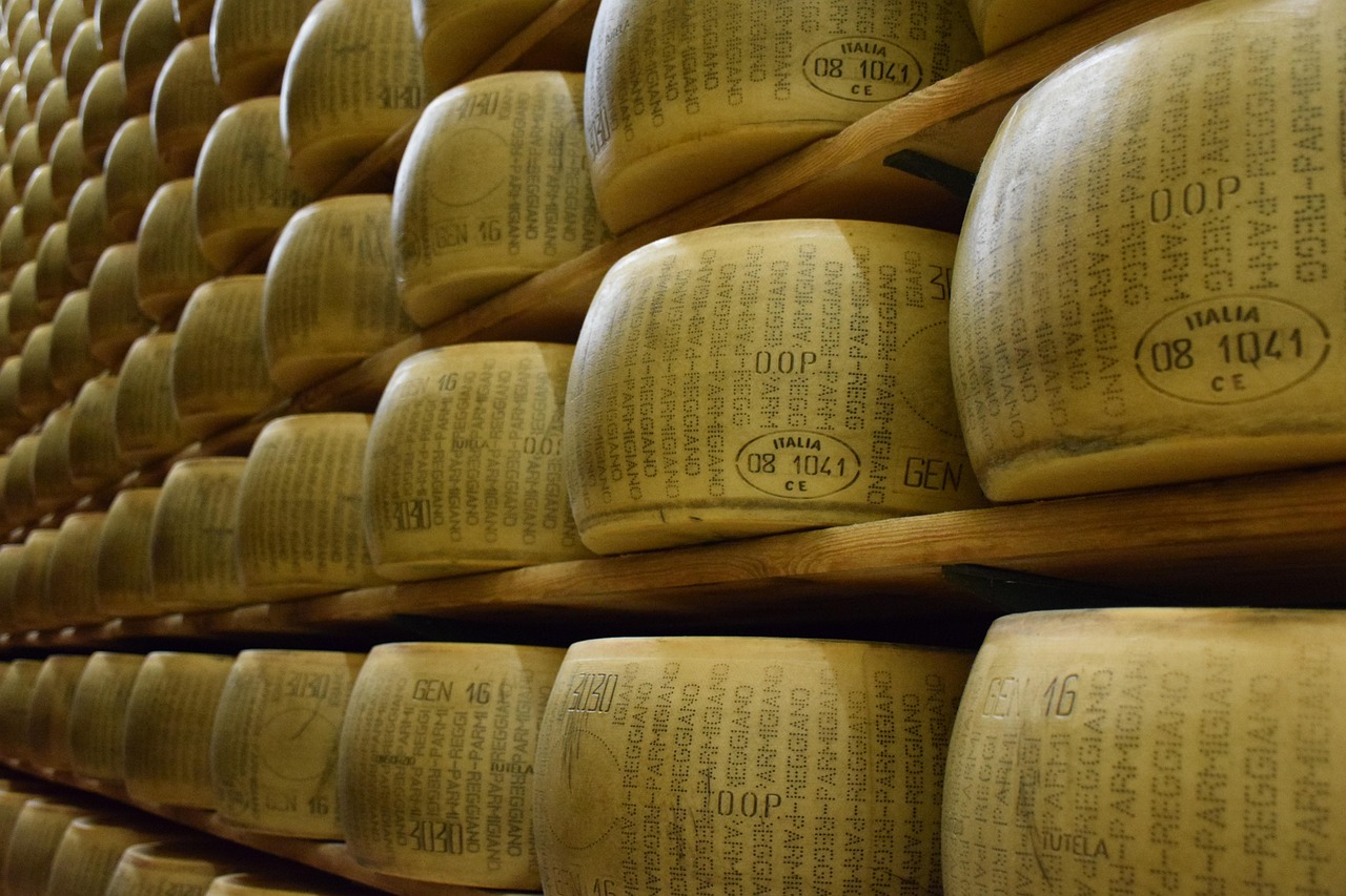 Visita guidata in un caseificio del borgo del parmigiano, con formaggi in esposizione e turisti curiosi.