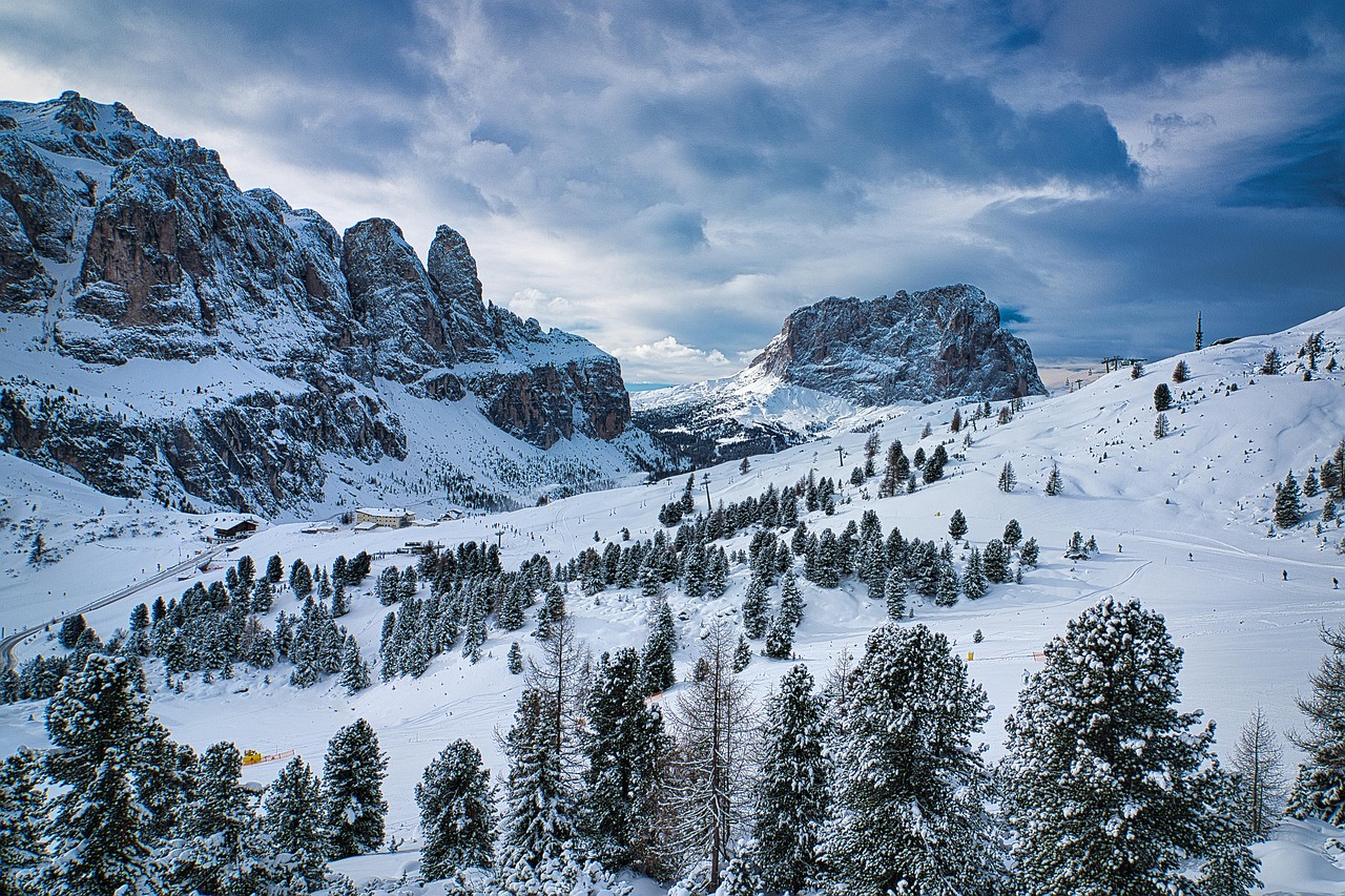 Panorama innevato delle Dolomiti, con valli e cime montuose illuminate dal sole in inverno.