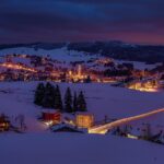 Coppia abbracciata in una pittoresca località invernale con paesaggio innevato e atmosfera romantica.