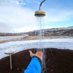 Uomo che si rilassa in una pozza termale circondata da neve in un paesaggio invernale.
