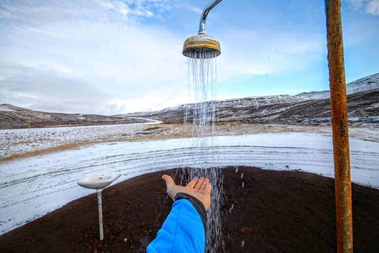 Uomo che si rilassa in una pozza termale circondata da neve in un paesaggio invernale.