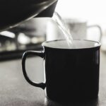 Tazza di acqua calda fumante su un tavolo, simbolo di benessere mattutino.